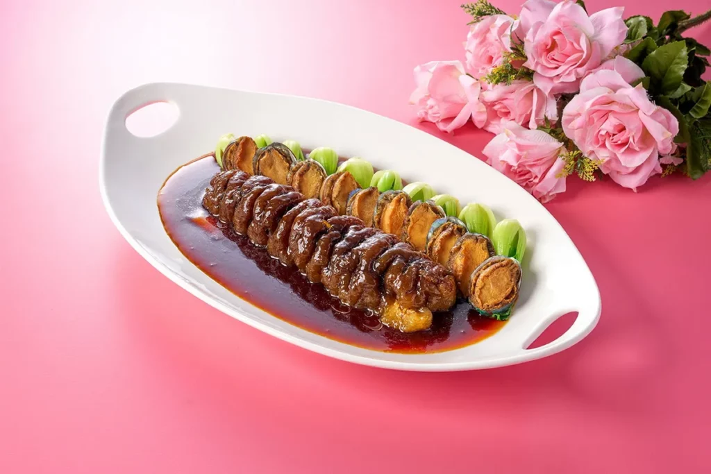 「干煎鮑魚黑玉參」嚴選整條頂級黑玉烏參入菜,搭配鮮嫩彈牙的鮑魚,以細火乾煎鎖住食材精華,口感滑順且富含膠質,交織出鮮醇濃潤的層次風味。(瀚寓酒店提供)