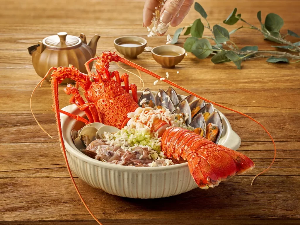 「文蛤小卷龍蝦泡飯」先以魚骨細火熬製濃白高湯,再加入粥底煮開後依序加入文蛤、小卷、水姑娘龍蝦等海鮮食材,最後撒入高溫炸製的酥脆米粒,湯頭清鮮甘醇,口感十足。(瀚寓酒店提供)