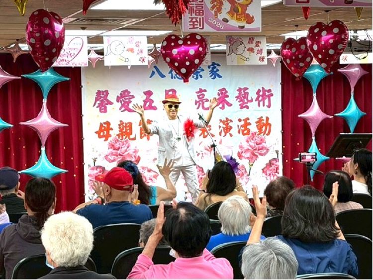 母親節前夕慰問八德榮家 亮采藝術團隊馨愛五月送暖 56 《圖說》亮采藝術關懷團隊表演者於舞台上帶動氣氛(前方),透過熱情演出與互動引領住民長輩一同揮手響應,現場掌聲與笑聲不斷,洋溢歡樂與感動。〈八德榮家提供〉