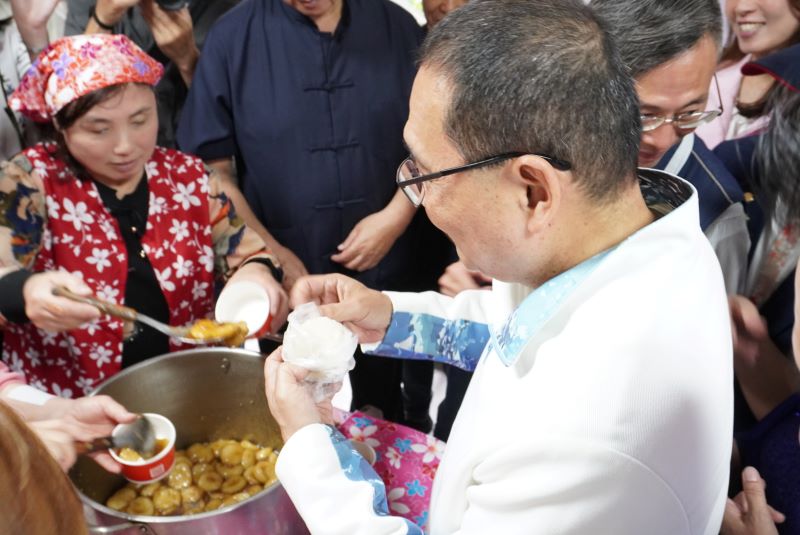 新北第10座哈客館啟用 侯「八年十館」達標 39 《圖說》侯友宜市長在活動現場的美食區與鄉親話家常,並品嚐客家菜包,氣氛熱鬧、溫馨。〈客家局提供〉