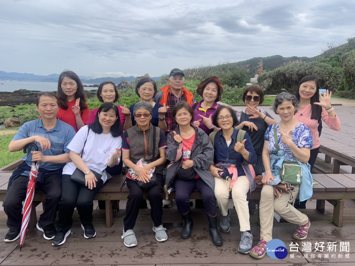 社工室林吉勝主任(前排左1)與志工夥伴於野柳海岸景觀前合影,留下珍貴同樂時光