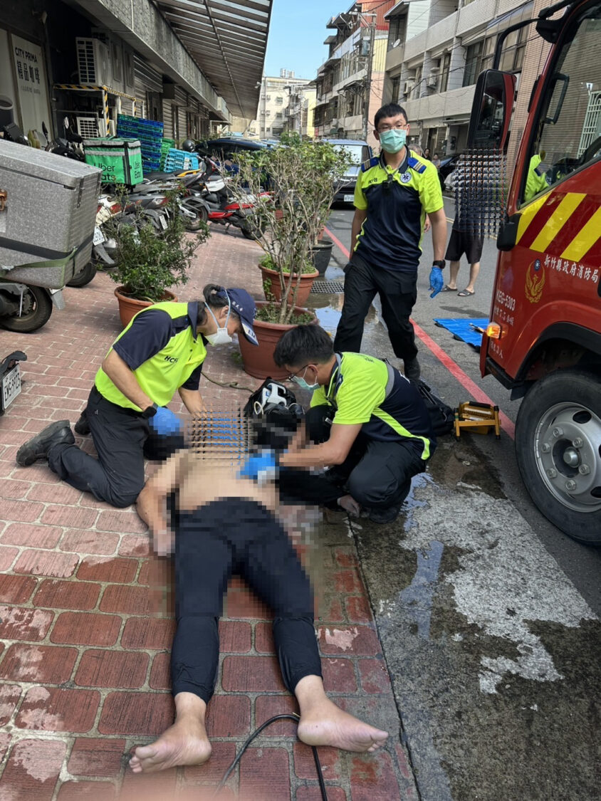 新竹縣政府消防局救護人員於竹東鎮民族路化糞池工安意外現場,緊急替昏迷工人實施急救處置,並持續進行生命徵象監測。(圖/記者張家燁翻攝)