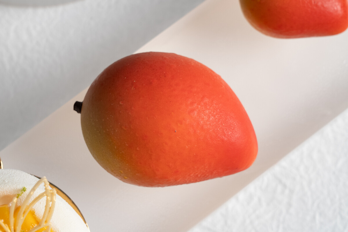 ▲芒果 Mango以仿真水果工藝詮釋台南玉井愛文芒果。可可脆殼包覆香草乳酪慕斯與芒果果肉。（圖/高雄洲際酒店提供）