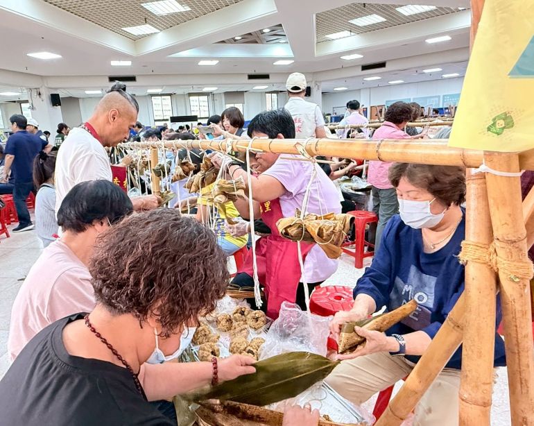 《圖說》里長、志工認真包粽，齊心協力完成一串串充滿祝福的粽子。〈板橋公所提供〉