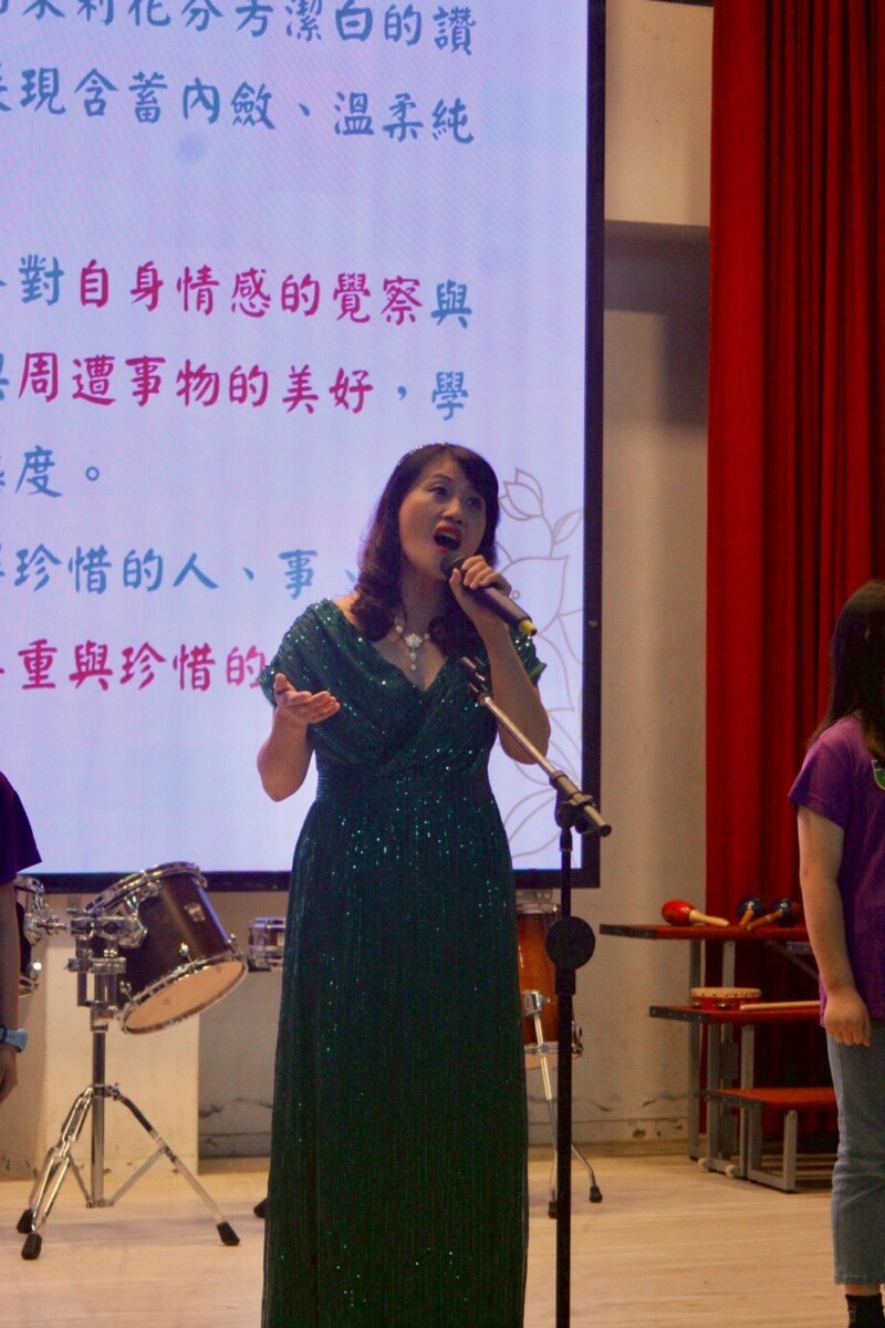 王春綢校長登台，以真誠歌聲與沉穩氣度唱出茉莉花這首名曲，展現教育者「以身示範」的力量。(影像由記者郭晉嘉拍攝)。