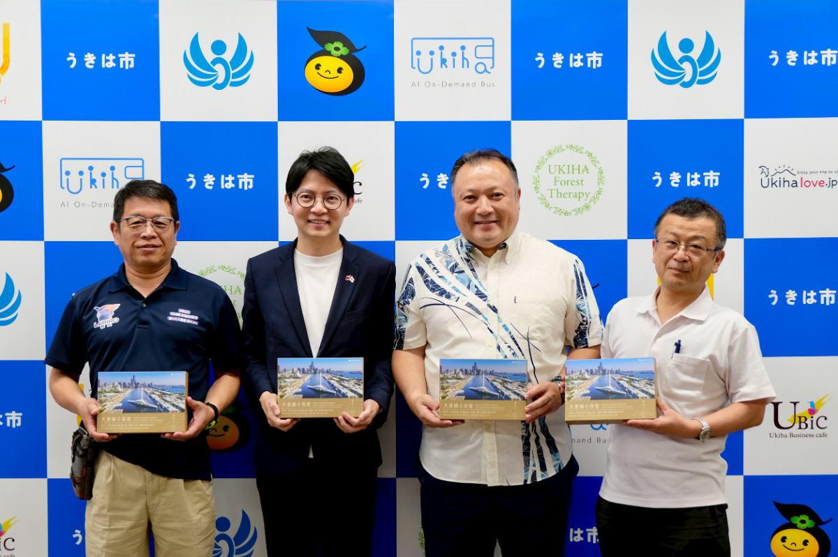 ▲青年局長林楷軒(左二)致贈5月浮羽市代表團來訪參加「台浮緣日」活動時,曾經過的大港橋地景予浮羽市長權藤英樹(右二)、浮羽市商工會會長堤先生(左一)與浮羽市觀光未來發展公社代表久次先生(右一),象徵兩地交流情誼持續深化。