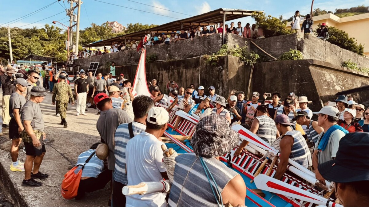達悟族大型拼板舟靠近巴丹島港口，岸邊族人迎接(圖/原住民委員會提供)