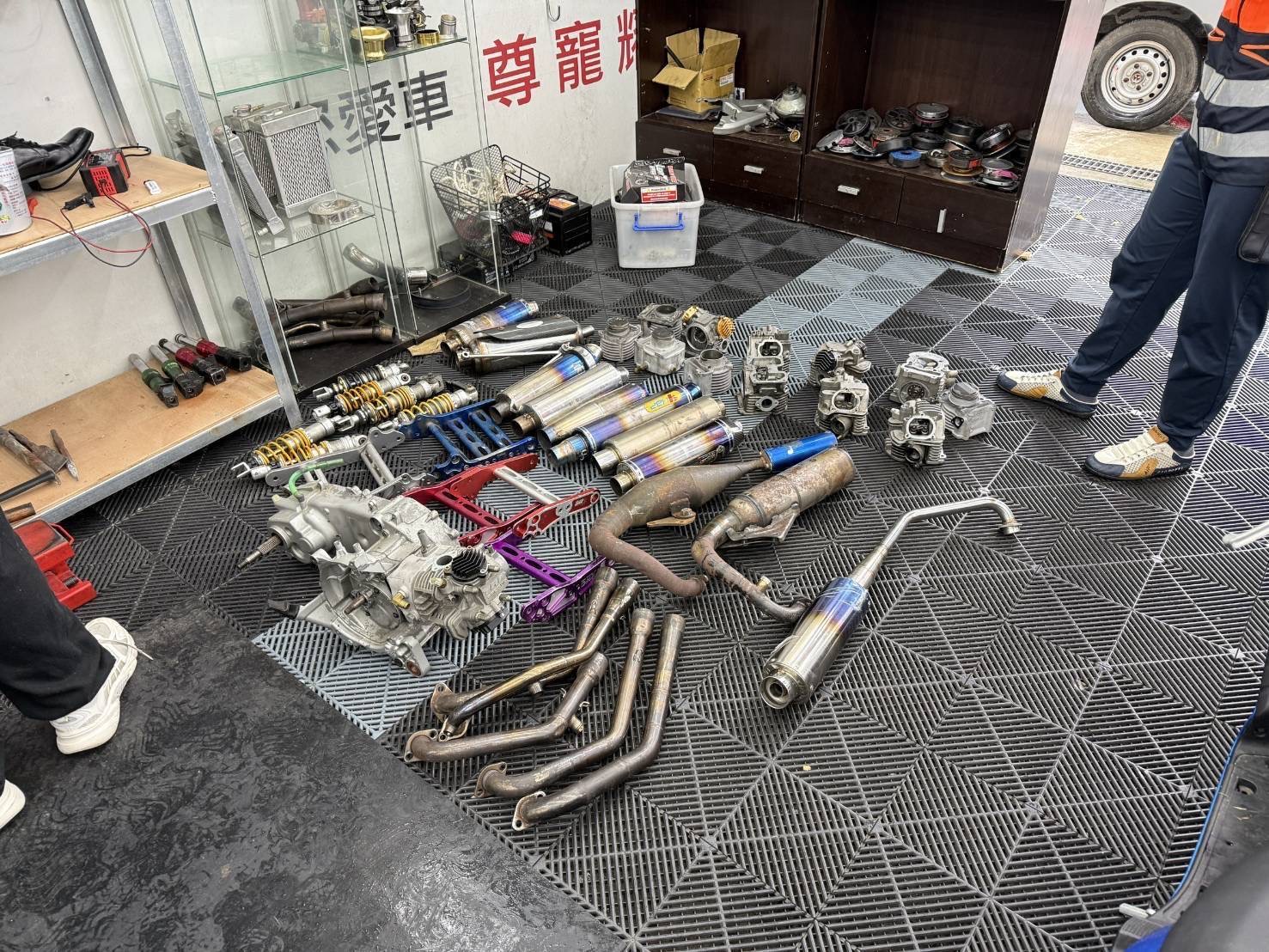 專案小組於車行內查獲大量改裝排氣管、避震器、引擎及車體零件等證物，作為追查飆車集團及非法改裝行為的重要依據。（圖／記者張家燁翻攝）