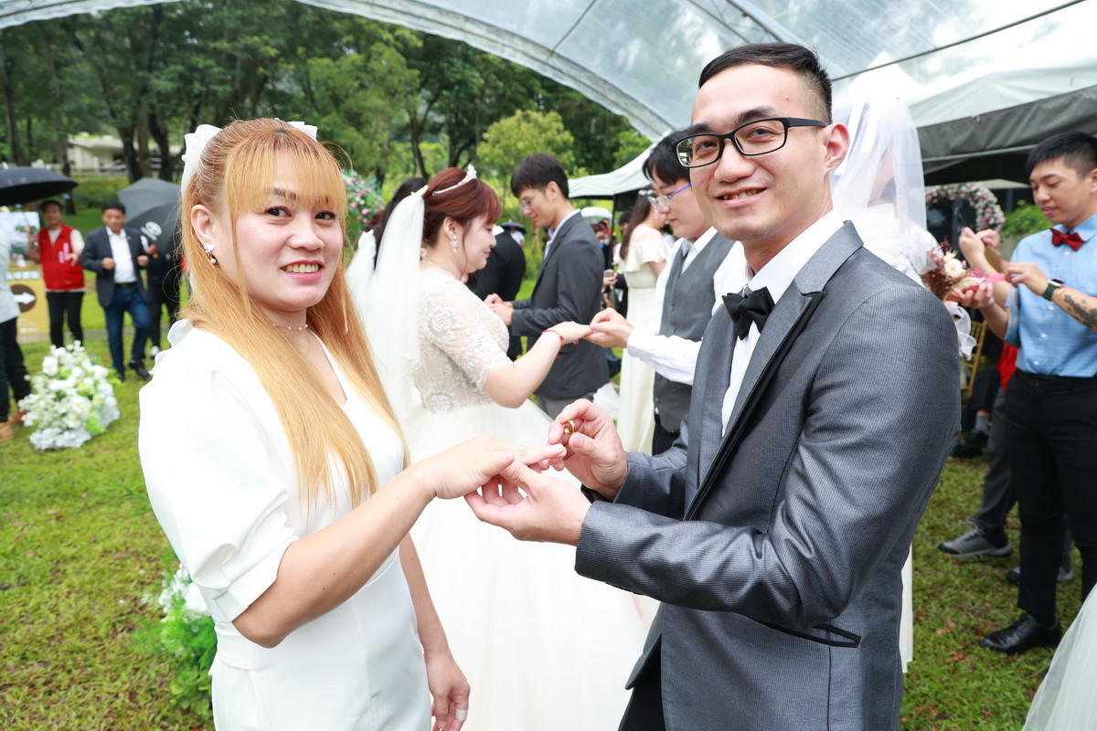 新人互戴婚戒，紫南宮贈每對新人金戒指祝福。（南投縣府提供）