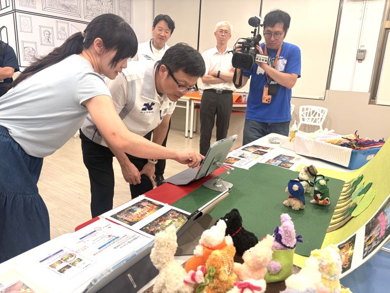 《圖說》陳品璇老師向局長示範藝術手作與AI工具應用結合產出如同電影海報般的作品，每個學生都可以學習使用AI工具讓自己的作品有不同呈現的樣貌。〈教育局提供〉