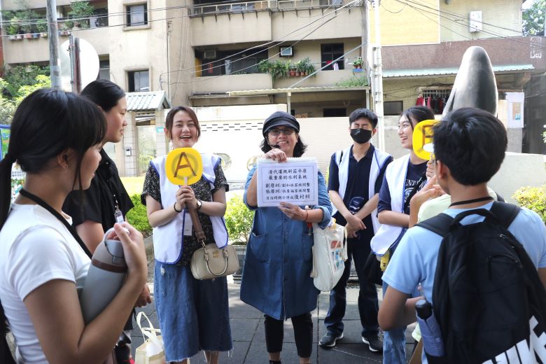 暑期走讀新莊老街 少年穿梭百年巷弄聽見歷史回聲 54 《圖說》新莊社區大學講師王惠靜(中)為兒少解說先人開墾新莊平原建設的劉厝圳、張厝圳,並要兒少搶答。左3為綽號「大飽」的新莊少年福利中心主任許巽絜。〈社會局提供〉