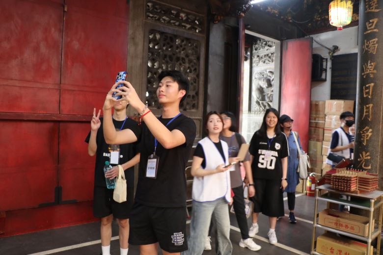 暑期走讀新莊老街 少年穿梭百年巷弄聽見歷史回聲 56 《圖說》參加文化走讀的兒少,循跡比對改建後的新楹聯。〈社會局提供〉