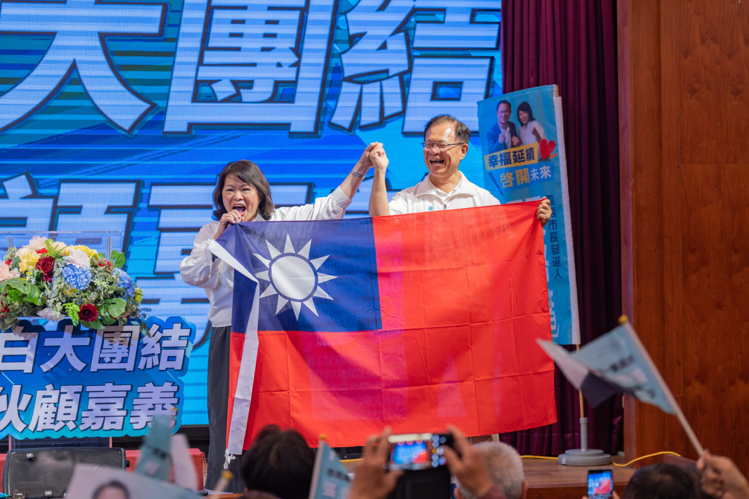 黃敏惠在活動中親自贈送一面大型國旗給張啓楷,象徵市政交棒。(圖/記者翻攝)