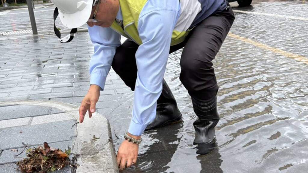 ▲巴威風雨釀落葉堵排水孔,林世賢冒雨巡查清除改善積水。(圖/記者林明佑翻攝)
