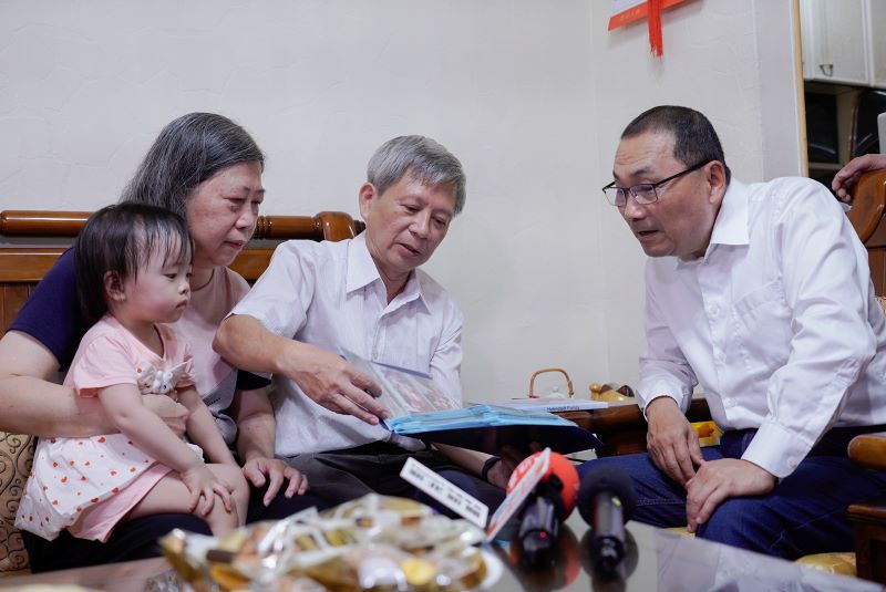 父愛跨越血緣 陳應興24年照顧16名寄養童榮膺模範父親 30 《圖說》陳應興與侯友宜市長分享照顧每位寄養童的照片和故事,左為太太劉仙珍抱著孫女。〈社會局提供〉