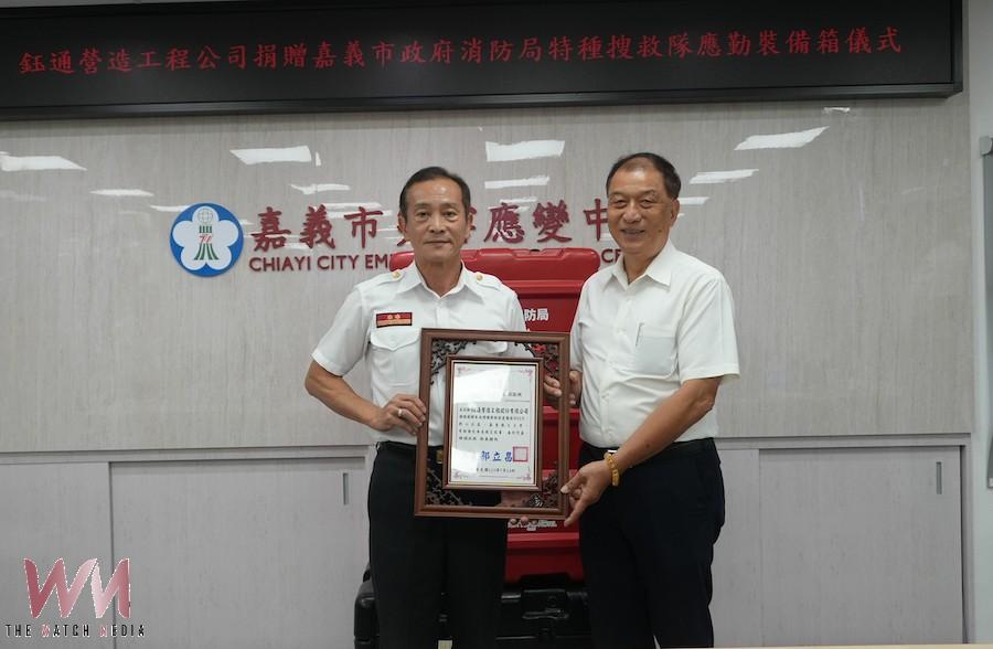 鈺通營造公司黃國芳董事長(右)捐贈嘉義市消防局20個特搜裝備箱,郭立昌局長(左)代表受贈並回贈感謝狀。(圖/嘉義市消防局提供)