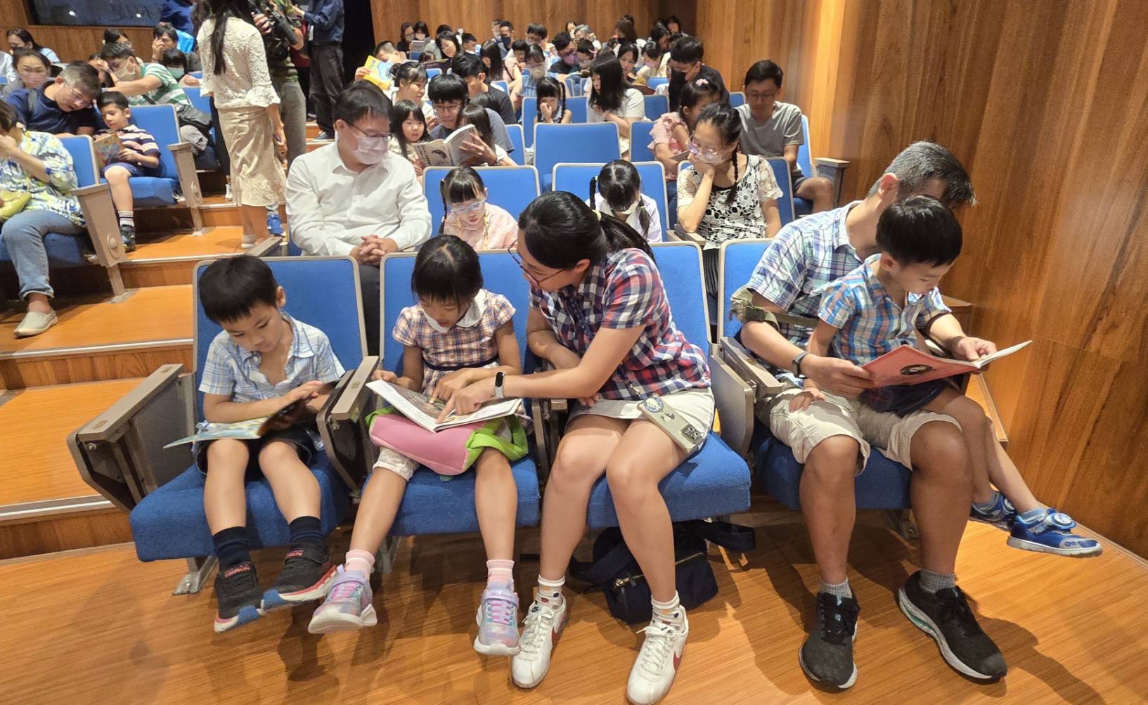 演奏廳內多組家庭同時低頭閱讀,家長陪伴孩子翻開書頁,親子對話與童聲交織成活動最具人文溫度的風景。