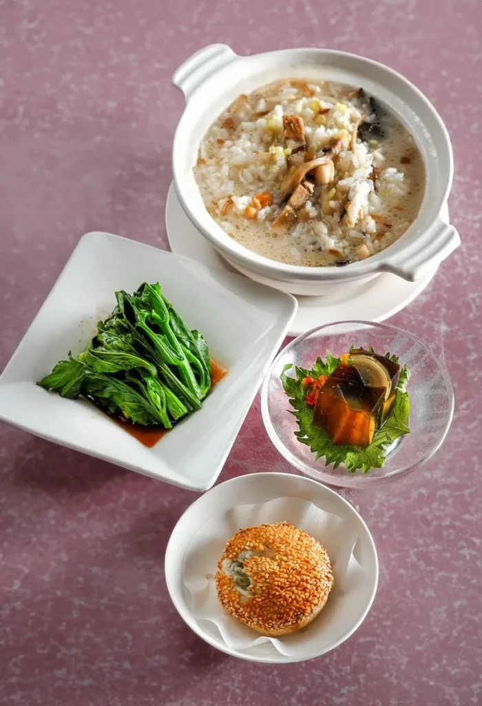 暖胃香菇肉粥搭配燒焦皮蛋凍、蠔油芥藍及外酥內香的蘿蔔絲酥餅，呈現「王朝早安．當港點遇見台味」週末套餐的豐富層次，每套320元，另加一成服務費。圖／台北凱撒大飯店提供