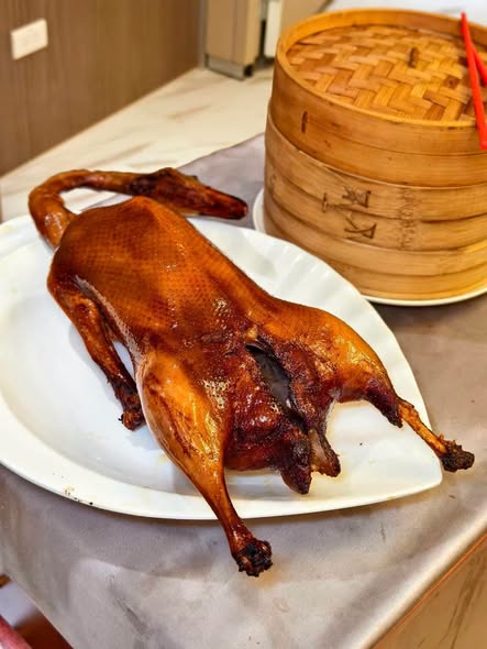 片製招牌片皮鵝,搭配蔥段、小黃瓜與特製甜麵醬,以薄餅包裹入口,酥脆鴨皮與鮮嫩鵝肉交織,展現道地粵式片皮料理的層次風味。圖/周含鍾攝
