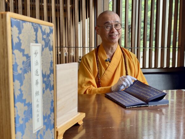法藏大和尚向記者介紹，由僧伽林文化出版有限公司發行的《妙法蓮華經》泥金復刻古美術，鎮宅與收藏價值。圖/楠西萬佛寺
