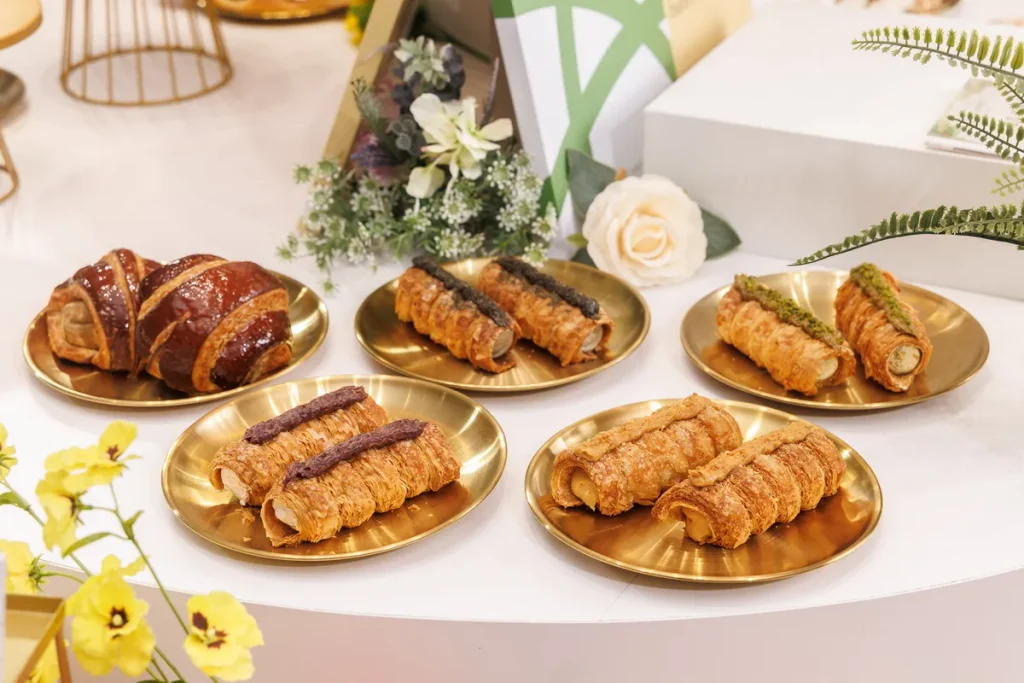 本次新品焦點「杜拜金絲丹麥捲」系列,推出「翡翠開心果」、「醇香厚花生」、「濃焙黑芝麻」與「薰衣草藍莓」等 4 種豐富口味,以酥香丹麥層次結合杜拜金絲口感;「烤地瓜丹麥」則將地瓜的自然香甜融入酥香丹麥麵包,透過植優烘焙用油細緻堆疊口感,為熟悉的經典風味帶來創意詮釋。