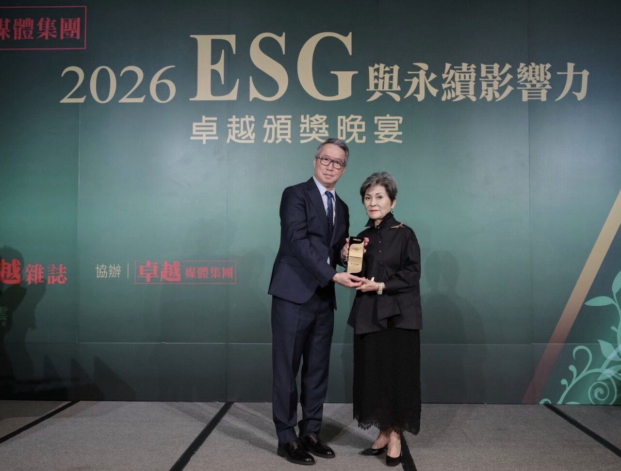 卓越媒體集團徐邦浩社長（左）頒贈「卓越永續終身貢獻獎」，由故尹衍樑總裁二姐尹衍桓女士代表受獎。
