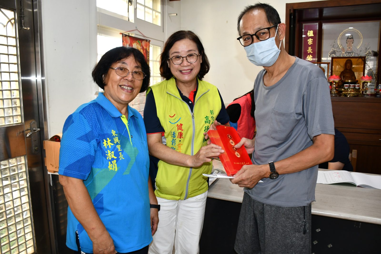 市長夫人高德耘（中）在東興里長林淑娟陪同下代表林世賢市長發放重陽敬老禮金與麵線