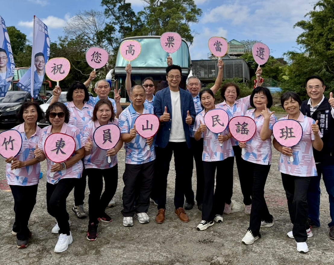 羅俊傑與竹東員山民謠班成員合影,成員手持「祝您高票當選」字牌,表達祝福。(圖/主辦單位提供)